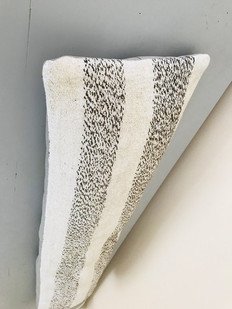 May include: A white and brown striped pillow with a textured surface.