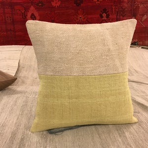May include: A beige and green throw pillow with a textured fabric. The pillow is made of two different fabrics, one beige and one green.