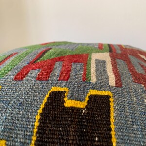 May include: A blue, green, red, white, black, and yellow patterned throw pillow with a geometric design.