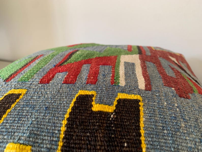 May include: A blue, green, red, white, black, and yellow patterned throw pillow with a geometric design.