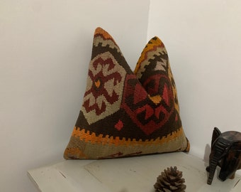 May include: Two decorative throw pillows with a geometric pattern in shades of brown, red, orange, and beige. The pillows are made of woven fabric and have a traditional design.