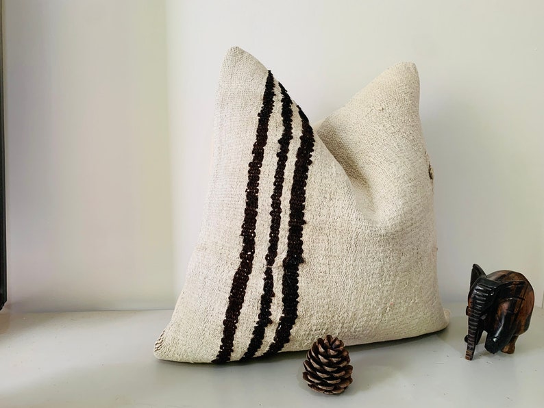 May include: A white throw pillow with three black stripes down the side. The pillow is made of a soft, textured fabric.