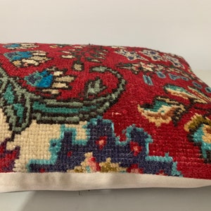 Puede incluir: Una almohada de tiro con estampado rojo, blanco y azul con un dise&ntilde;o floral. La almohada est&aacute; hecha de una tela suave y tejida y tiene un borde blanco.