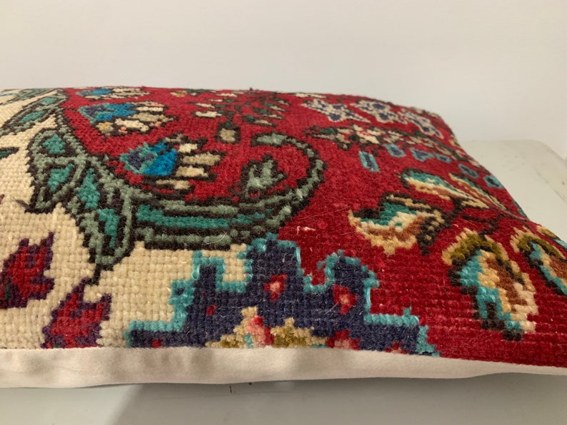 Puede incluir: Una almohada de tiro con estampado rojo, blanco y azul con un dise&ntilde;o floral. La almohada est&aacute; hecha de una tela suave y tejida y tiene un borde blanco.