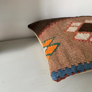 May include: A brown, orange, blue, and white patterned throw pillow with a geometric design.