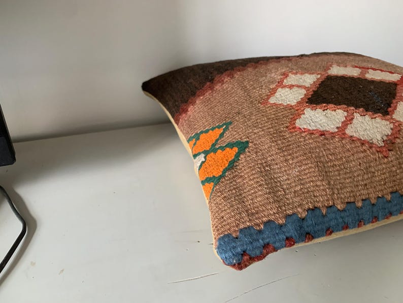 May include: A brown, orange, blue, and white patterned throw pillow with a geometric design.