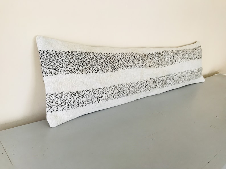 May include: A long white and black striped bolster pillow with a subtle speckled pattern.