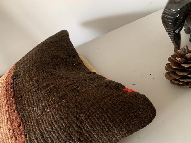 May include: A brown and orange woven throw pillow with a textured surface.