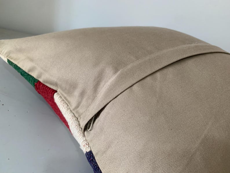 May include: A beige pillow with a zipper closure. The pillow has a colorful striped pattern on the front.