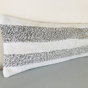 May include: A long, white lumbar pillow with black stripes. The stripes are made of small, black dots.
