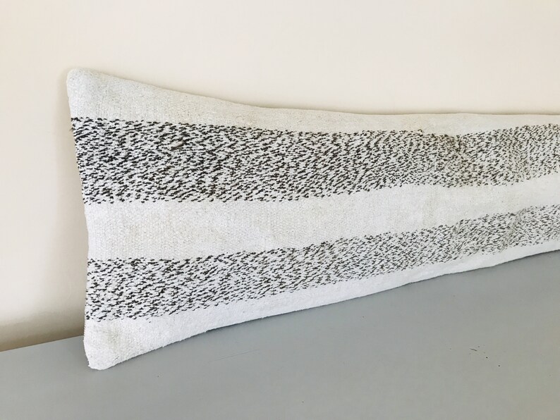 May include: A long, white lumbar pillow with black stripes. The stripes are made of small, black dots.