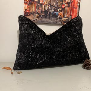 May include: Black and white patterned throw pillow with a soft, textured fabric. The pillow is rectangular and has a subtle sheen.