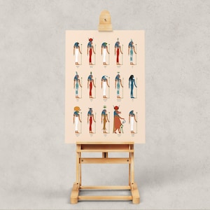 Puede incluir: Un p&oacute;ster con ilustraciones de dioses y diosas egipcios. El p&oacute;ster est&aacute; en un caballete de madera y tiene un fondo beige claro. Las ilustraciones son de estilo tradicional con colores vibrantes y detalles intrincados. Los dioses y diosas est&aacute;n representados de perfil, cada uno con un tocado y atributos &uacute;nicos.
