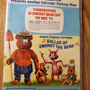 May include: A vintage poster advertising a Thanksgiving special on NBC-TV featuring Smokey Bear. The poster features a cartoon illustration of Smokey Bear with other forest animals, including a fox, a squirrel, an owl, and a turtle. The text on the poster reads "Thanksgiving is Smokey Bear Day on NBC-TV."  James Cagney narrates "Ballad of Smokey the Bear".  The poster also includes information about the show's air date and time.