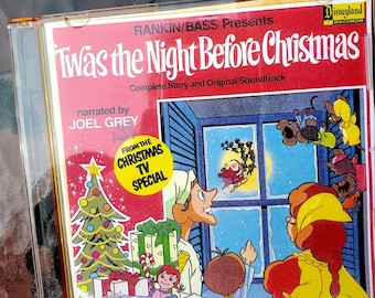 May include: A red CD case with a picture of a Christmas scene. The title is "Twas the Night Before Christmas" with the text "Complete Story and Original Soundtrack" and "narrated by JOEL GREY". The text "FROM THE CHRISTMAS TV SPECIAL" is in a yellow circle.