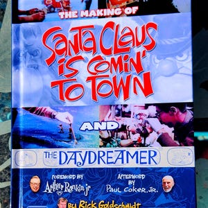 May include: Book cover with a blue background and the title "The Making of Santa Claus is Comin' to Town and The Daydreamer". The cover features images from the animated film, including Santa Claus, a reindeer, and a snowman. The book is by Rick Goldschmidt, with a foreword by Arthur Rankin Jr. and an afterword by Paul Coker Jr.
