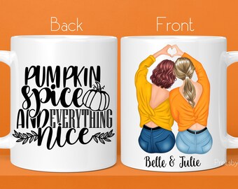 May include: White ceramic mug with a black and white design on the back that says "Pumpkin Spice and Everything Nice". The front of the mug features a cartoon illustration of two women with brown hair wearing yellow and blue outfits. The text "Belle & Julie" is printed below the illustration.