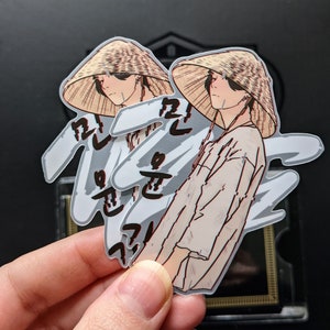 May include: Two stickers featuring a cartoon character wearing a straw hat and a white shirt. The character is standing in front of a white background with black text that reads "길을 잃은 꽃" in Korean.