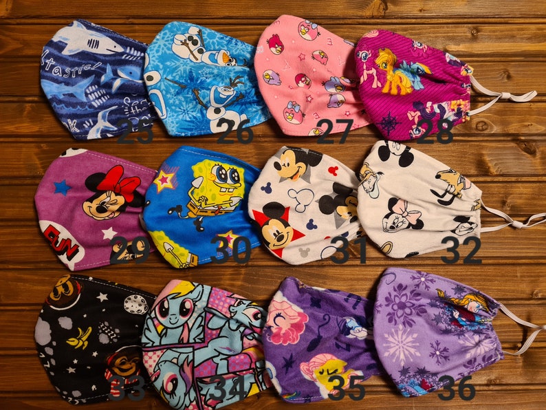 May include: A set of 12 colorful fabric face masks with various cartoon characters, including Mickey Mouse, SpongeBob SquarePants, Frozen characters, and My Little Pony. The masks are numbered 25 through 36.