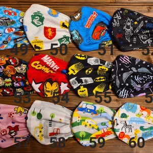 May include: A set of 10 colorful fabric face masks with various designs, including cars, superheroes, Sesame Street characters, and Harry Potter. The masks are numbered 49 through 60.