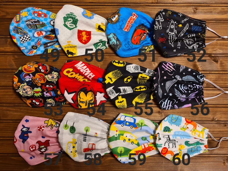 May include: A set of 10 colorful fabric face masks with various designs, including cars, superheroes, Sesame Street characters, and Harry Potter. The masks are numbered 49 through 60.