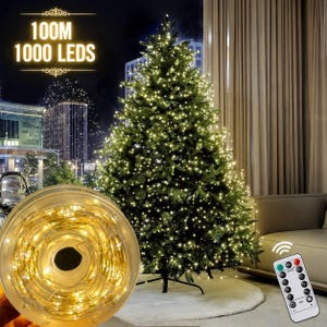 Könnte beinhalten: Ein hoher künstlicher Weihnachtsbaum mit warmweißer Beleuchtung, dazu eine Spule mit 100M 1000 LED-Lichterkette und eine Fernbedienung. Der Baum hat dichte grüne Zweige und steht auf einem Metallständer.