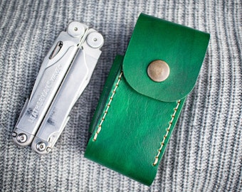 May include: A silver multi-tool with the text "Leatherman Wave" on the side, in a green leather case with a brass button.