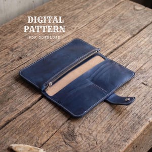 Könnte beinhalten: Eine marineblaue Ledergeldbörse mit einem Reißverschlussfach, mehreren Kartenfächern und einem Druckknopfverschluss. Der Text DIGITAL PATTERN PDF DOWNLOAD ist oben links im Bild zu sehen und weist auf eine Bastelvorlage hin.