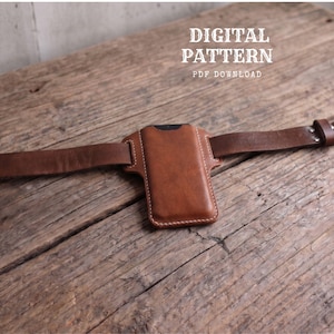 May include: A brown leather phone holster with white stitching, designed to slide onto a belt. The text DIGITAL PATTERN PDF DOWNLOAD is visible in the upper right corner. The holster features a rectangular pouch with rounded corners.