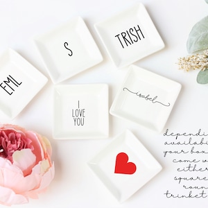Puede incluir: Seis bandejas cuadradas blancas con diferentes dise&ntilde;os. Los dise&ntilde;os incluyen las palabras "EML", "S", "TRISH", "I LOVE YOU", "isabel" y un coraz&oacute;n rojo.