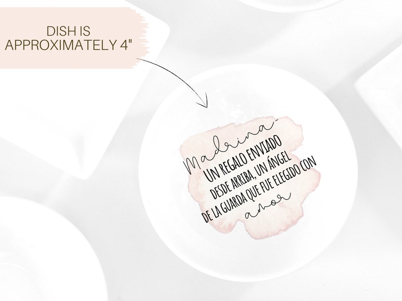 May include: A white ceramic dish with a pink watercolour design that says "madrina UN REGALO ENVIADO DESDE ARRIBA, UN &Aacute;NGEL DE LA GUARDA QUE FUE ELEGIDO CON amor".