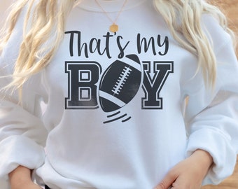 May include: White sweatshirt with the text "That's my Boy" in black lettering and a black and white football graphic.