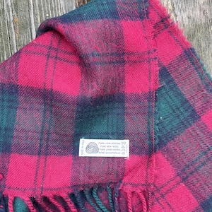 Könnte beinhalten: Roter und grüner karierter Wollschal mit Fransen. Der Schal hat ein Etikett mit der Aufschrift "Pura Lana Vergine, Pure New Wool, Pure Laine Vierge, Rene Schwoller, Made in Italy."