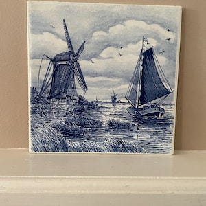 Cerámica vintage azul de Delft, estilo tradicional y pintada a mano con una escena de un molino de viento y un barco de vela.
