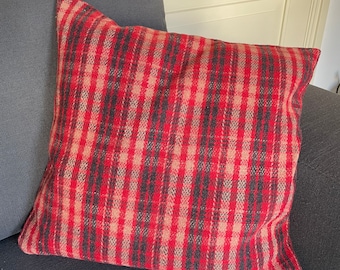 Könnte beinhalten: Ein rotes und schwarzes kariertes Kissen mit weichem, strukturiertem Stoff. Das Kissen liegt auf einem dunkelgrauen Sofa.