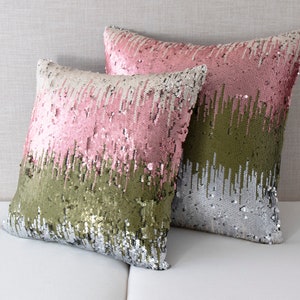 May include: Two decorative throw pillows with a reversible sequin design. One pillow is pink and green, the other is silver and green.