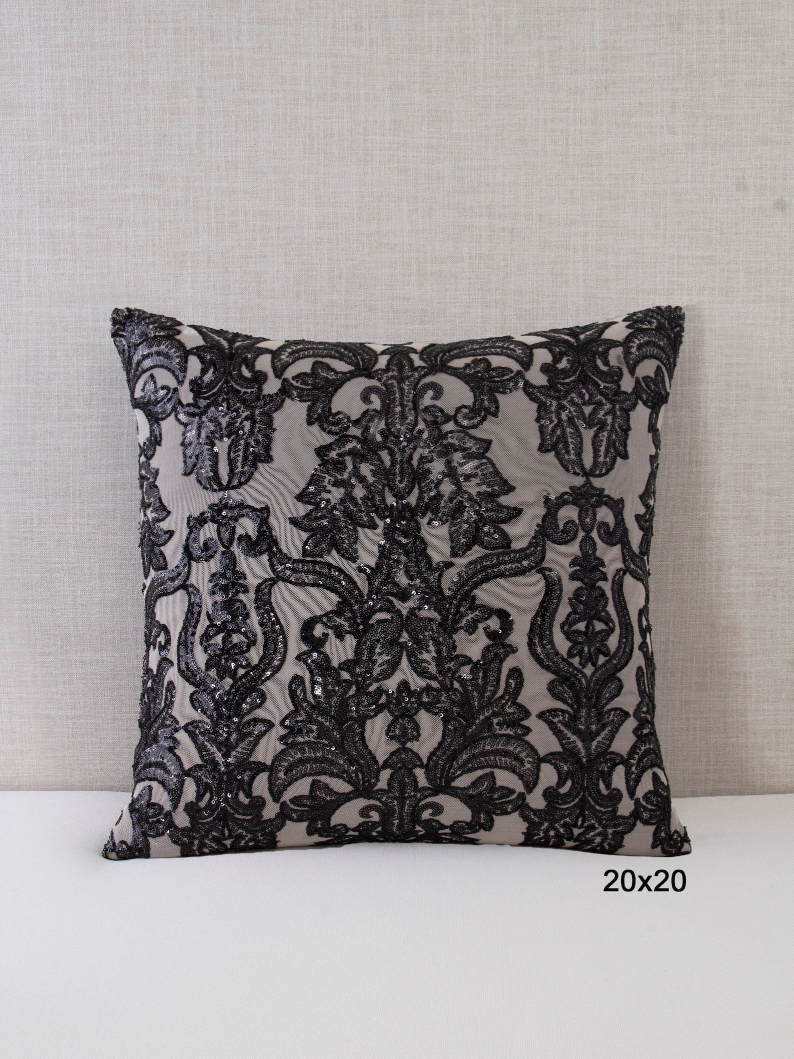 A single gray square throw pillow featuring ornate black damask sequin embroidery, displayed upright against a neutral fabric background