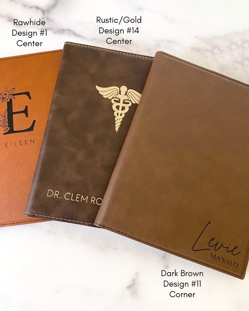 Peut inclure: Trois journaux reli&eacute;s en cuir avec des motifs et des noms diff&eacute;rents. Le premier journal est brun avec le nom "Eileen" et le texte "Rawhide Design #1 Centre". Le deuxi&egrave;me journal est brun avec le texte "DR. CLEM RO" et "Rustic/Gold Design #14 Centre". Le troisi&egrave;me journal est brun avec le texte "Levie MANALO" et "Dark Brown Design #11 Corner".
