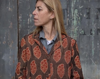 May include: A brown patterned blazer with red accents. The blazer has a button closure and long sleeves. The sleeves have red trim.