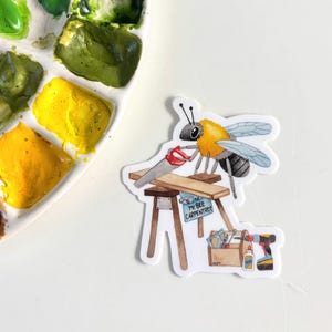 May include: A sticker featuring a cartoon bee carpenter sawing wood. The bee has yellow and black markings, with a saw, toolbox, and the text "Mr. Bee Carpentree". A paint palette with green and yellow paint is in the background.