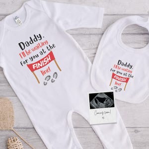 Könnte beinhalten: Weißes Baby-Set mit Strampler und Lätzchen mit dem Text "Daddy, I'll be waiting for you at the FINISH line!" und einem Ultraschallfoto mit "Coming soon!". Der Strampler hat eine Ziellinien-Grafik.