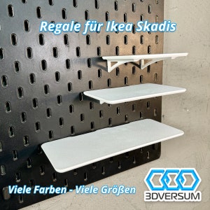 Può includere: Tre mensole bianche per un pannello forato Ikea Skadis. Le mensole sono in plastica e hanno una finitura liscia e opaca. Il testo "Regale für Ikea Skadis" è visibile nella parte superiore dell'immagine. Il testo "Viele Farben - Viele Größen" è visibile nella parte inferiore dell'immagine. Il logo "3DVERSUM" è visibile nell'angolo in basso a destra dell'immagine.