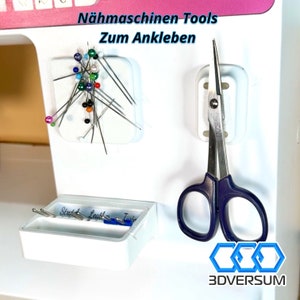 Könnte beinhalten: Weißes Nähmaschinen-Zubehörset mit einem magnetischen Nadelkissen, einem magnetischen Scherenhalter und einem kleinen Fach mit drei Fächern, die mit "Stud", "Leather" und "Twin" beschriftet sind.