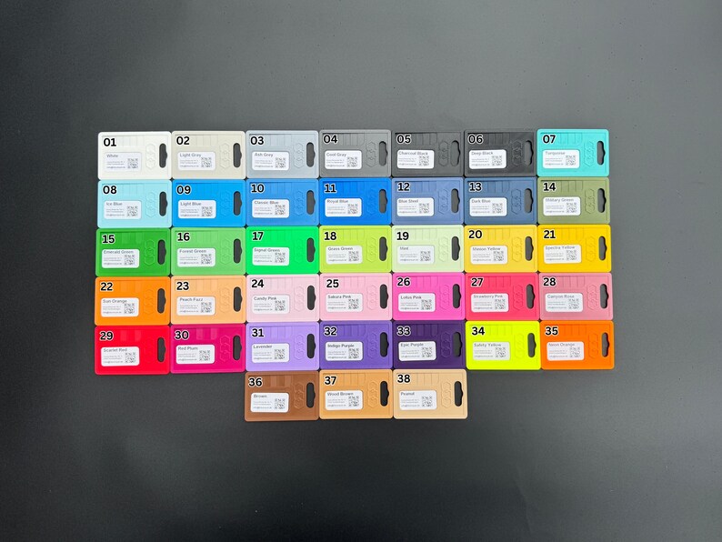 May include: A collection of 38 color swatches, each with a unique number and color name. The swatches are arranged in rows and columns, showcasing a variety of hues, including blue, green, pink, and yellow. Each swatch has a small hole.