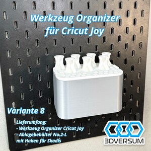 May include: A silver and white tool organizer for Cricut Joy, with the text "Werkzeug Organizer f&uuml;r Cricut Joy" and "Variante 8". The organizer has multiple slots for tools and is designed to be mounted on a pegboard.