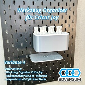 May include: A gray and white tool organizer for Cricut Joy, mounted on a black pegboard. The organizer has multiple compartments for tools and a separate tray. Text on the image reads "Werkzeug Organizer f&uuml;r Cricut Joy" and "Variante 4".