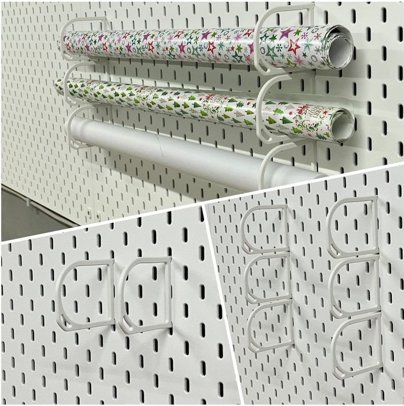 K&ouml;nnte beinhalten: Wei&szlig;er Geschenkpapier-Organizer aus Metall mit drei Ebenen, der Geschenkpapierrollen h&auml;lt. Das Geschenkpapier hat festliche Muster mit Sternen, Weihnachtsb&auml;umen und anderen Urlaubsdesigns. Der Organizer ist an einer wei&szlig;en Lochwand befestigt.