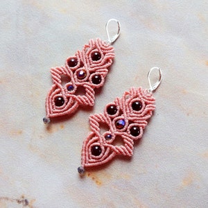 May include: A pair of pink macrame earrings with dark purple beads and silver hooks.