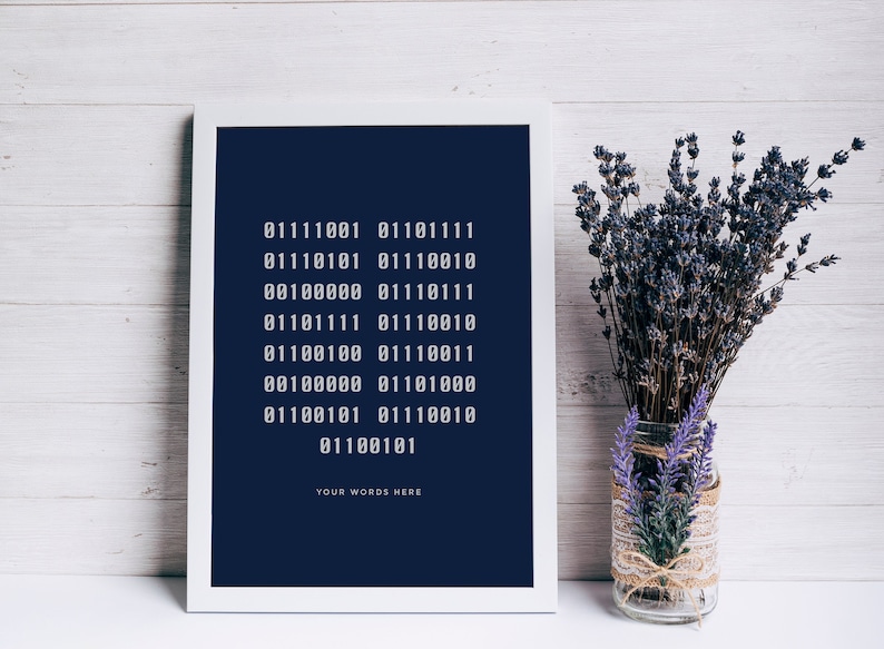 Puede incluir: Una impresi&oacute;n enmarcada en blanco con un fondo azul oscuro y texto blanco. El texto es una serie de c&oacute;digo binario con las palabras "YOUR WORDS HERE" en la parte inferior. La impresi&oacute;n est&aacute; sobre una superficie de madera blanca junto a un jarr&oacute;n de vidrio con lavanda seca.