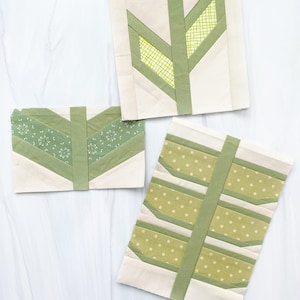 May include: Three fabric squares with a green and white leaf design. The squares are made of different fabrics with different patterns, including polka dots, small floral prints, and a grid pattern.